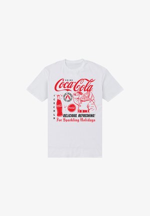 Coca-Cola-tema hvid t-shirt med røde og sorte grafikker, herunder en flaske, Julemanden og tekst, der promoverer en forfriskende juledrink.