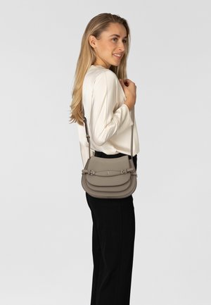 Sac bandoulière en cuir gris clair, doté d'un design à couches multiples, de ferrures argentées et d'une sangle réglable. Texture lisse avec des accents subtils.