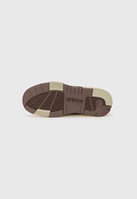 Brown rubber shoe sole with textured pattern, including raised sections and a lighter beige heel, branded with "HUGO" on the midsole.