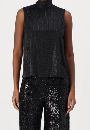 Ärmelloses schwarzes Highneck-Oberteil aus Mesh, kombiniert mit schwarzen Paillettenhosen, gezeigt an einem Model von Hals bis Mitte Oberschenkel.