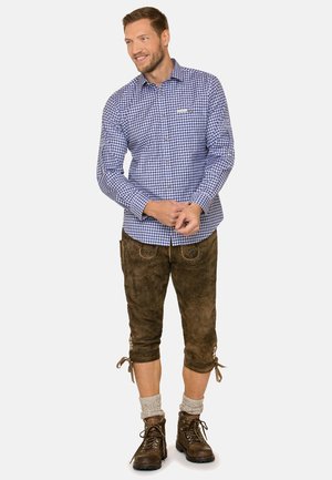 Blau-weiß kariertes Hemd mit langen Ärmeln, kombiniert mit braunen knielangen Shorts und braunen Wanderschuhen. Strukturiertest Gewebe mit Knöpfen.