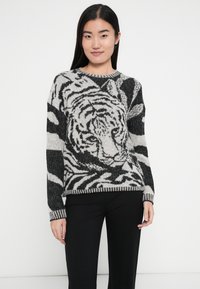 Schwarz-weiß gestrickter Pullover mit einem Tiger-Motiv und Zebraprints, mit rundem Ausschnitt sowie gerippten Bündchen und Saum.