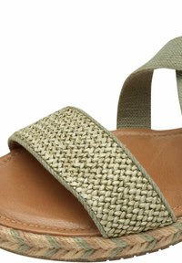 Sandalo open-toe con fascia intrecciata verde, sole in pelle color caramello e suola in juta con bordo intrecciato. Design piatto per il comfort.