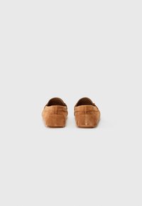 Brown suede loafers with a flat sole and a rounded toe, featuring minimal stitching and slip-on design.