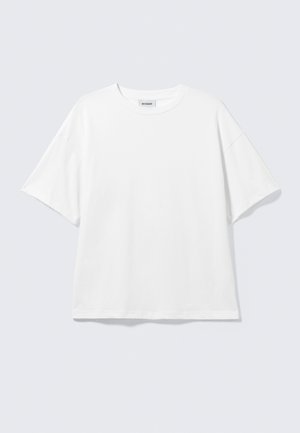 Λευκό φαρδύ T-shirt με κοντά μανίκια και στρογγυλή λαιμόκοψη με χαμηλωμένους ώμους, επίπεδο σε ανοιχτό γκρι φόντο.