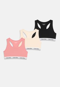 Trzy sportowe biustonosze Calvin Klein w kolorach różowym, beżowym i czarnym, z białymi elastycznymi paskami z logo Calvin Klein.