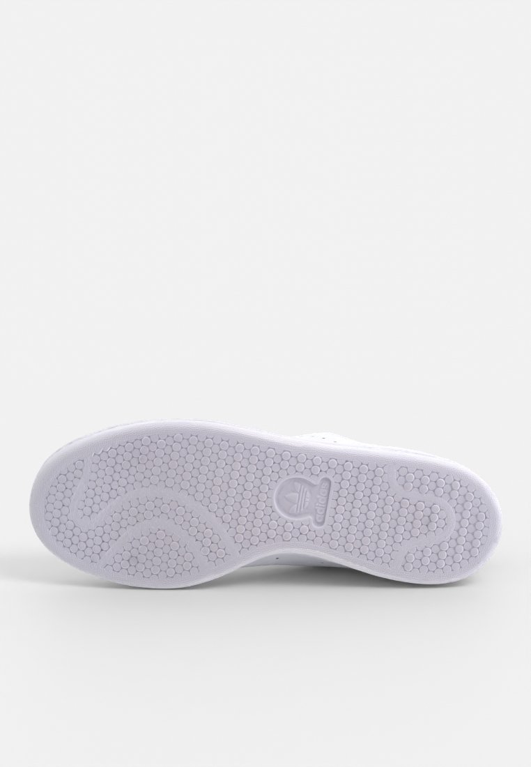 Semelle de sneaker en caoutchouc blanc avec une texture hexagonale, présentant un logo bien en vue et des lignes de design courbées pour une adhérence et une flexibilité accrues.