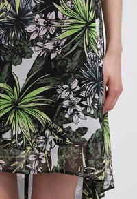 Průhledné šaty s květinovým vzorem, na černém pozadí s zelenými listy a růžovými květinami; asymetrický lem; lehký materiál.