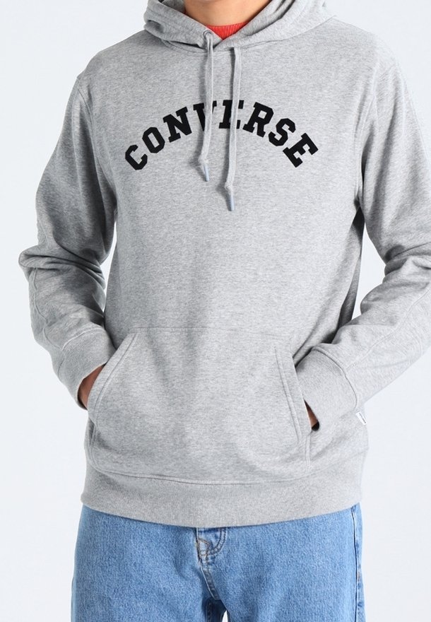 Gray hoodie made of soft material featuring a front pocket, drawstring hood, and "CONVERSE" curved text in black. Casual design with ribbed cuffs.