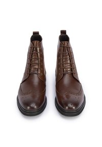 Botas de tobillo de cuero marrón con un acabado suave, diseño de cordones, detalles decorativos de brogue y suela de goma negra.