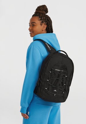 Sac à dos noir avec une surface texturée, équipé de bretelles ajustables, d'un design avec cordon élastique à l'avant, et d'un petit logo.
