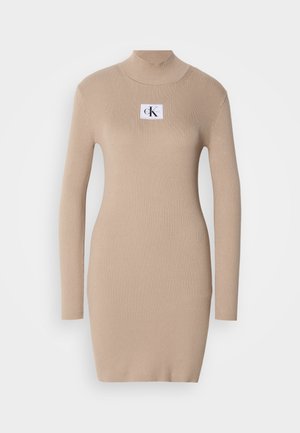Beige Strickkleid mit Stehkragen, langen Ärmeln, Rippstruktur und quadratischem Logopatch auf der Brust. Figurbetonter, knielanger Schnitt.