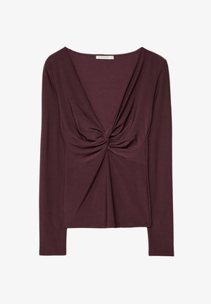 Burgundowa bluzka z długim rękawem z przekręconym przodem, wykonana z miękkiego, elastycznego materiału. Ma głęboki dekolt w kształcie V i dopasowany krój.