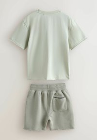 Mátově zelené bavlněné tričko s krátkými rukávy, doplněné o odpovídající sportovní kraťasy s elastickým pasem a boční kapsou.