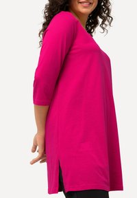 Fuchsia tuniektop met een relaxte pasvorm, driekwartmouwen, zijsplitsingen aan de onderkant en een gladde katoenstof.