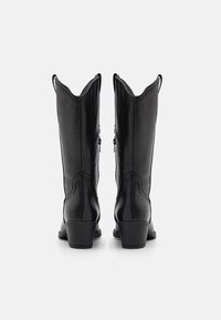 Botas occidentales de cuero negro con punta afilada, detalles de costura y tacón cuadrado, con lengüetas de tirón para un fácil acceso.