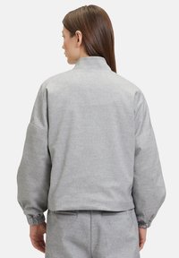 Grijze bomberjack met een gestructureerde afwerking, voorzien van een hoge kraag, elastische manchetten en een cropped silhouet. Eenvoudig ontwerp met strakke lijnen.