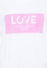 Vitt tyg med en rosa rektangel som innehåller ordet "KÄRLEK" och mindre text: "Allt vi gör – gör vi med passion. Kärlek och hjärta. Mos Mosh."