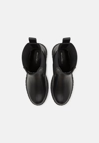 Svarta läderankelboots med elastiska sidopaneler, rund tå och texturerad gummisula, med varumärket inuti och en ögla baktill.