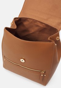 Sac à main en cuir marron avec rabat ouvert, montrant un intérieur spacieux, un fermoir magnétique doré, et une poche zippée à l’avant avec tirette en cuir.