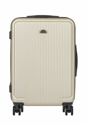 Kremowa walizka twarda z pionowymi żebrowaniami, czarnymi kółkami oraz czarnym logo marki umieszczonym centralnie w górnej części przedniego panelu.