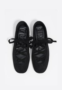 Czarne zamszowe baleriny z krzyżującymi się sznurkami i zaokrąglonym noskiem. Wnętrze zawiera wytłoczone logo na czarnej powierzchni.