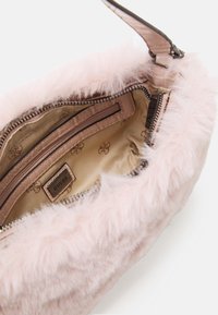 Jasnoróżowa torebka z futerka ekologicznego z zamkiem błyskawicznym, wyposażona w gładką podszewkę wewnętrzną oraz małą wewnętrzną kieszonkę z wytłoczonym logo.