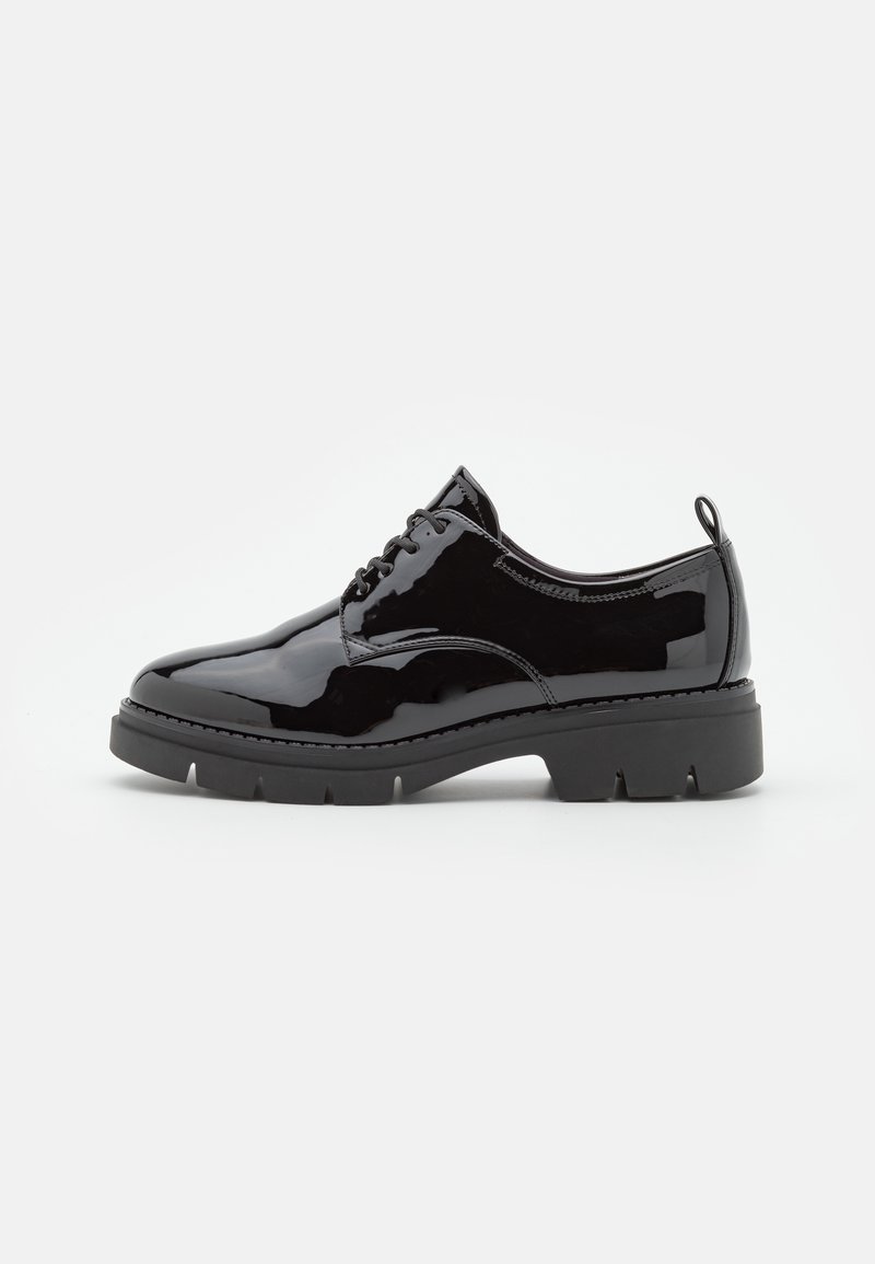 Chaussure à lacets en cuir verni noir avec semelle épaisse et languette au talon, présentée de profil sur un fond uni.