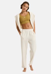 Beige sportieve crop top, hooggetailleerde witte sweatpants, zachte stof, elastische tailleband, minimalistisch ontwerp, geen zichtbare patronen of accenten.