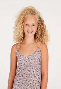 Robe sans manches rose à motifs floraux avec de fines bretelles, arborant des fleurs noires et blanches sur un fond clair, fabriquée en tissu léger.