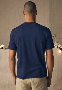 Mørkeblå kortærmet t-shirt lavet af bomuld, med en klassisk rund halsudskæring og en glat tekstur. Minimalistisk design, der understreger enkelhed.