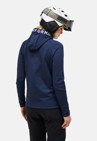 Navy performance hoodie with a front kangaroo pocket, fitted cuffs, and a hood. The back features a logo along the collar. Textured fabric.