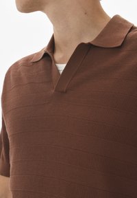 Barna textúrájú, rövid ujjú polo, V-nyakkal és bordázott gallérral, vízszintes csíkokkal. Nagyítás a kiváló anyagra és a dizájnra.