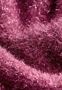 Tissu synthétique flou dans des nuances de rose, présentant une surface texturée et scintillante avec de longues mèches fines créant profondeur et douceur.