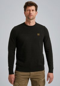 Zwart gestructureerd sweater met een ronde hals, lange mouwen en een klein gouden logo-opdruk op de borst. Zachte stof, aansluitend ontwerp.