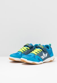 Niebieskie buty sportowe z szarymi akcentami, z siateczkowego materiału, jasne żółte sznurowadła, zapięcie na rzep oraz biała podeszwa z gumowym bieżnikiem.