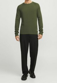 Khaki zelený hřejivý svetr s dlouhými rukávy, kulatým výstřihem, v kombinaci s černými kalhotami a černými šněrovacími botami. Jednoduchý, texturovaný design.