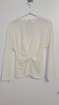 White long-sleeve blouse with a knotted back design, made from a lightweight, semi-sheer fabric. Features a relaxed fit and round neckline.