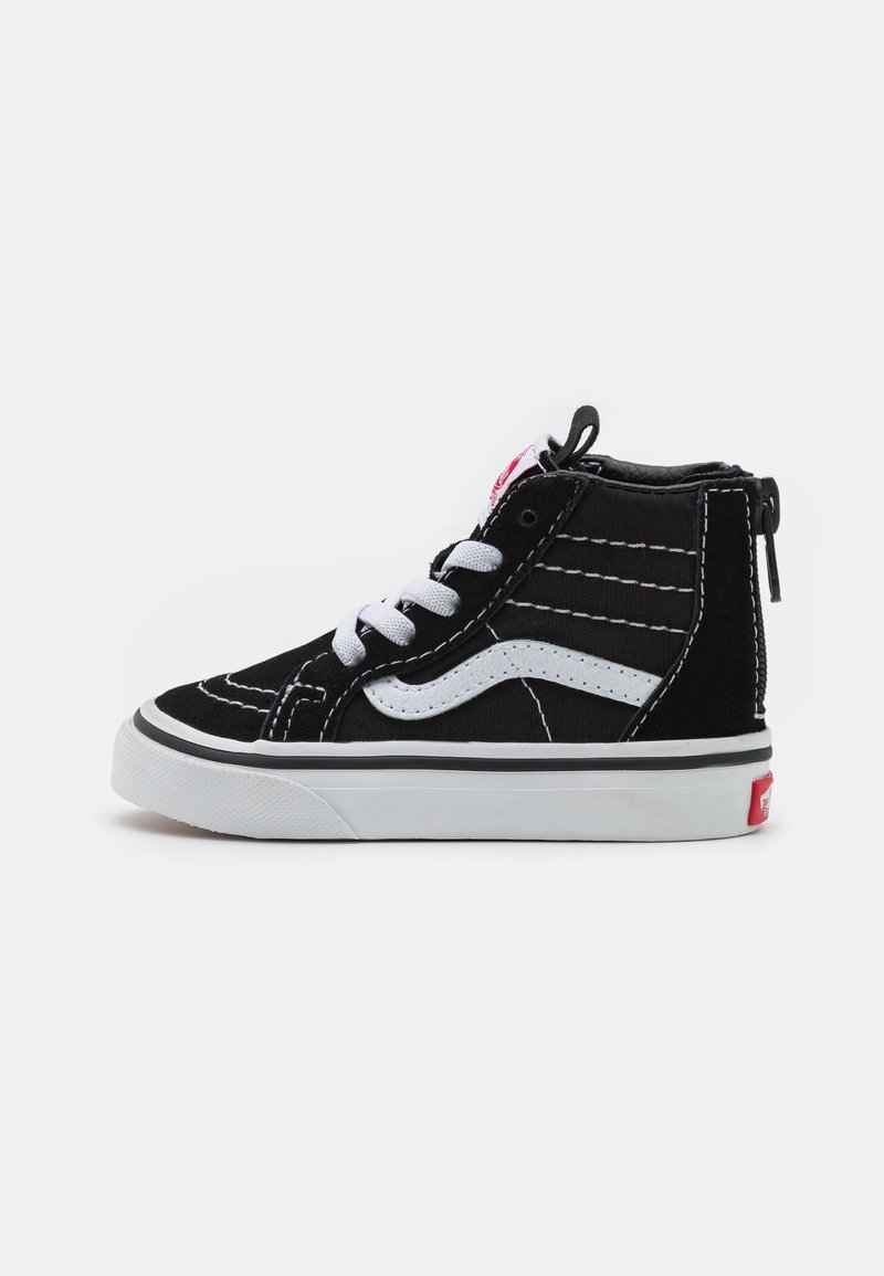 Baskets montantes noir et blanc avec lacets blancs, bande latérale, détails de couture et logo rouge sur le talon sur fond uni.