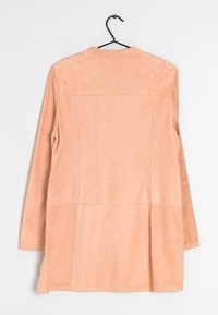 Persikofärgad läderjacka med en slät textur, långa ärmar och en något utsvängd nederkant; har sömdetaljer på baksidan.