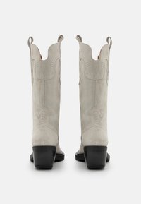 Halli halli nahast cowboy saapad terava varbaga, dekoratiivse õmblusega ja musta plokkkontsaga. Omab tõmblukke lihtsaks jalga panemiseks.