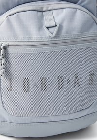 Light blue backpack featuring a mesh pocket with "JORDAN" text, smooth fabric, practical zippers, and contrasting accents. Durable design.