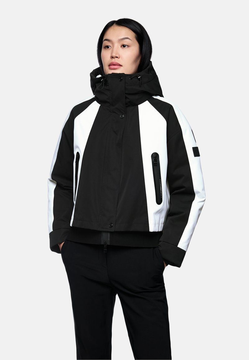 Schwarze und weiße Jacke mit Kapuze, cropped geschnitten, mit Reißverschluss-Taschen, kontrastierendem Panel-Design und elastischen Bündchen. Glatte Stoffoberfläche.