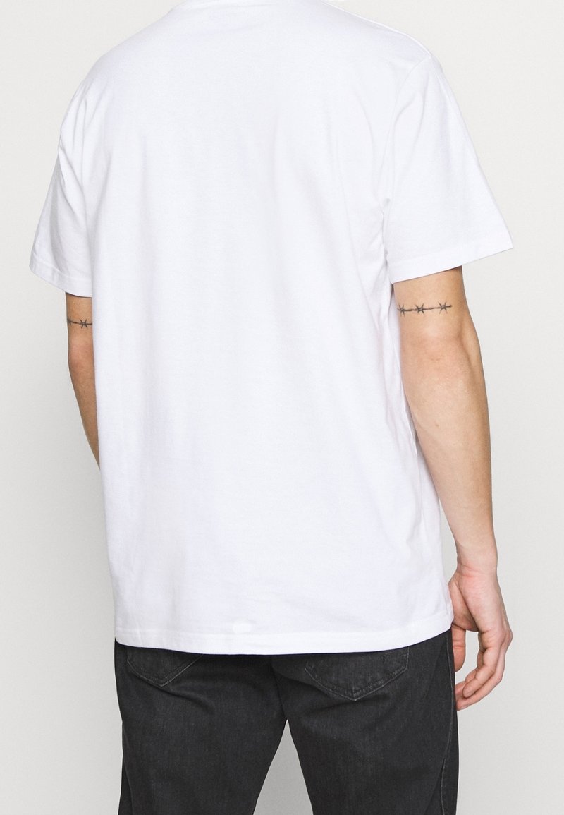 Camiseta de algodón blanca con mangas cortas, cuello redondo y un diseño liso. Presenta una costura trasera visible y una textura sutil.