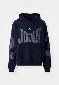 Mørkeblå hættetrøje med "JORDAN" grafik i grå, logo på brystet og teksturerede detaljer på ærmerne. Økologisk bomuldsstof med en lomme foran.