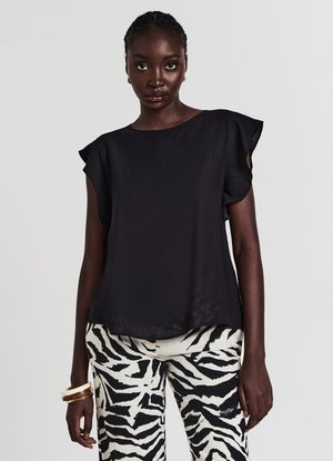 Haut noir léger avec manches courtes à volants, associé à un pantalon noir et blanc à motif zèbre. Texture lisse, coupe ample.