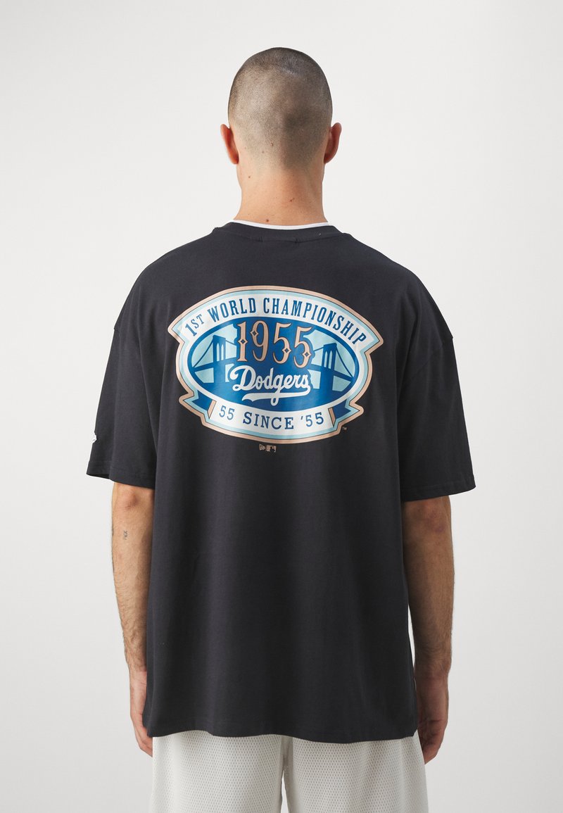 Camiseta negra con un gran gráfico en azul y dorado en la parte posterior, conmemorando el campeonato mundial de los Dodgers de 1955. Tejido de algodón, ajuste holgado.