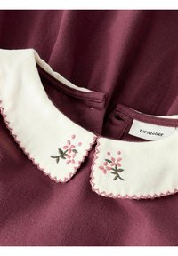 Burgunderfarbnes Kleid mit einem weißen, gewellten Kragen, der mit rosa und grüner Blumenstickerei verziert ist. Weicher Stoff, Knopfverschluss auf der Rückseite.