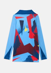 Camicia a maniche lunghe in tessuto azzurro chiaro con motivi geometrici astratti in rosso, blu navy e giallo, con colletto blu scuro.