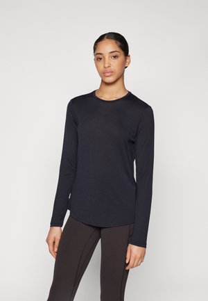Long-sleeve, lightweight top in dark navy, with a round neck and smooth texture. Paired with fitted black leggings.